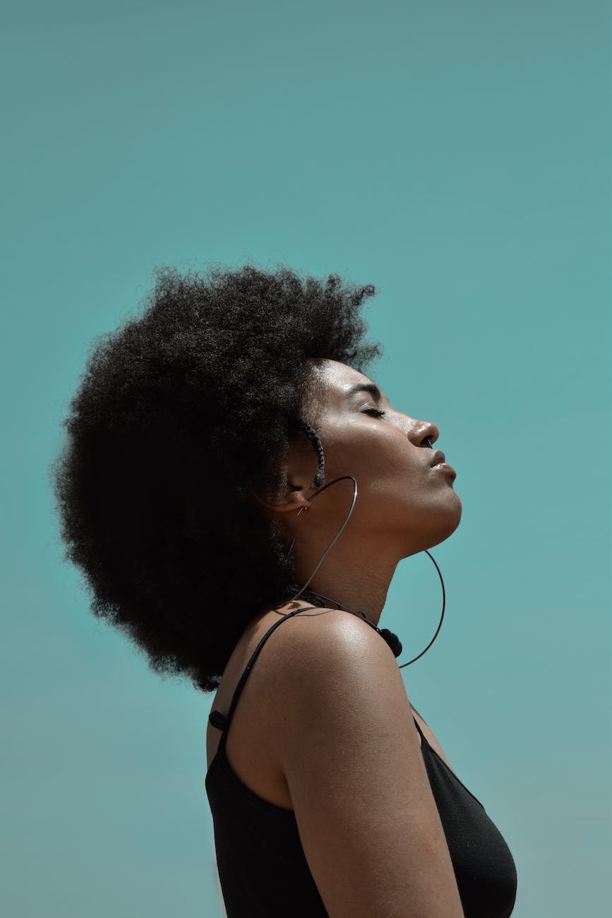 stylish dreamy black woman with afro hairstyle on blue background